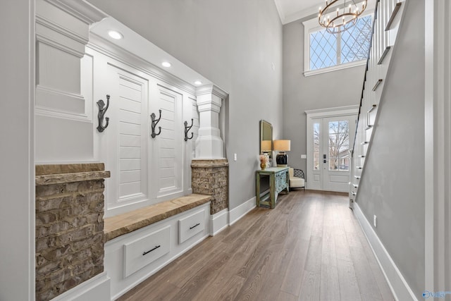 mudroom featuring a notable chandelier, wood-type flooring, and ornamental molding