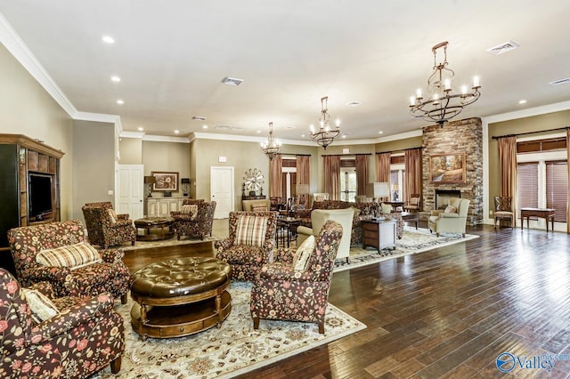 living room with an inviting chandelier, ornamental molding, dark hardwood / wood-style flooring, and a stone fireplace