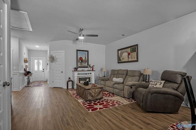 living room with ceiling fan, a tiled fireplace, and hardwood / wood-style floors