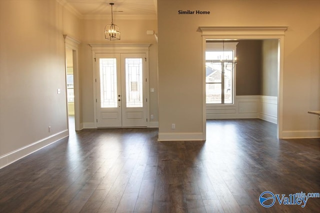 foyer entrance featuring dark wood finished floors, ornamental molding, and an inviting chandelier