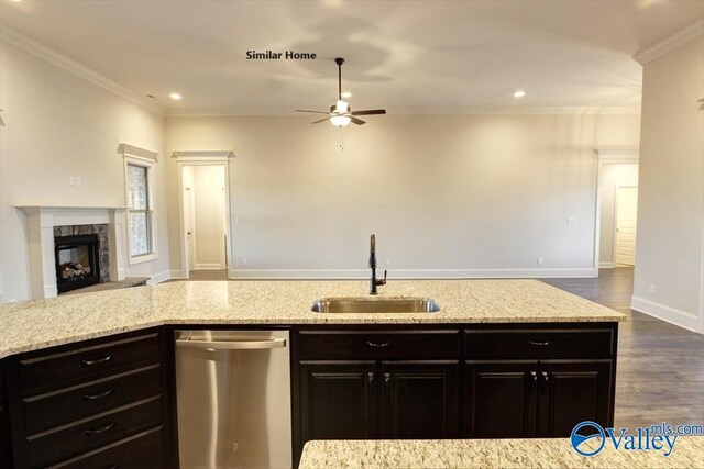 kitchen featuring stainless steel dishwasher, a sink, open floor plan, a ceiling fan, and light stone countertops