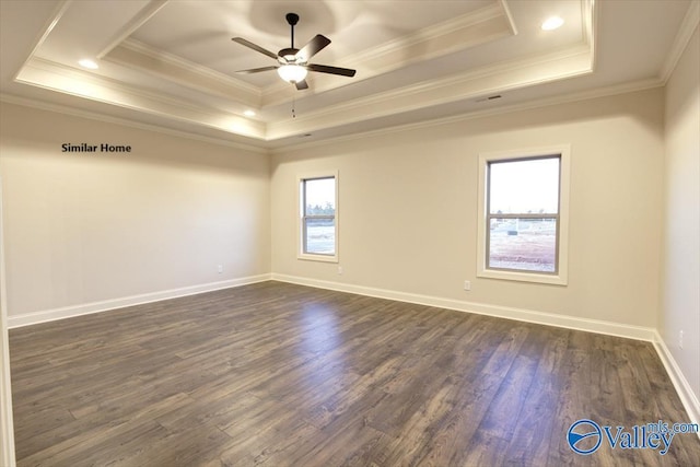 empty room featuring a tray ceiling, dark wood-type flooring, and ornamental molding