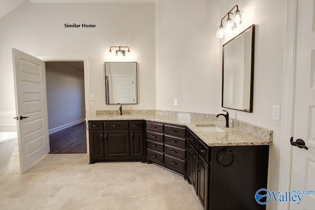 bathroom with double vanity, a freestanding tub, tile patterned flooring, and a sink