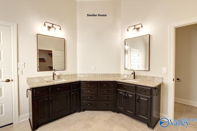 full bathroom with double vanity, tile patterned flooring, baseboards, and a sink