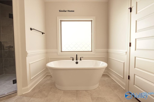 full bathroom featuring a soaking tub, tile patterned floors, wainscoting, and a shower stall