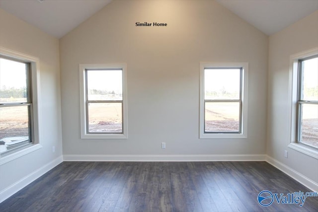 spare room featuring lofted ceiling, dark wood-style floors, and baseboards