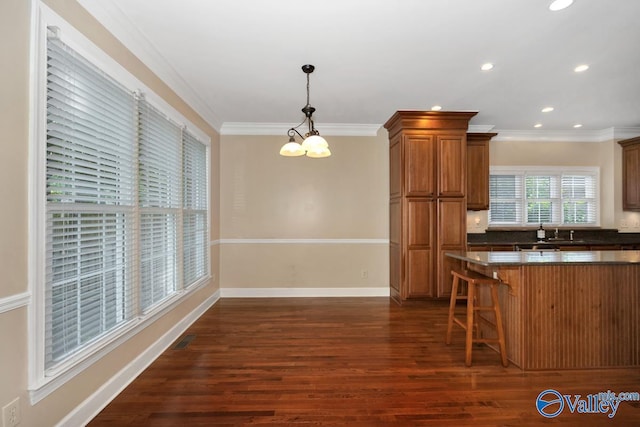 412 Clydebank Dr, Madison, AL 35758 - kitchen featuring dark countertops, a kitchen breakfast bar, ornamental molding, brown cabinetry, and dark wood-style flooring