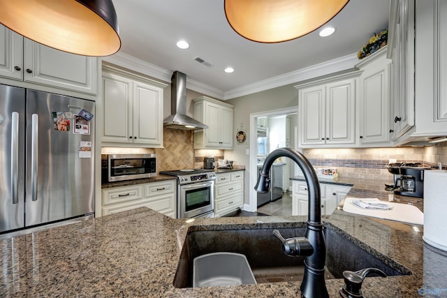 kitchen with dark stone counters, stainless steel appliances, wall chimney range hood, and white cabinets