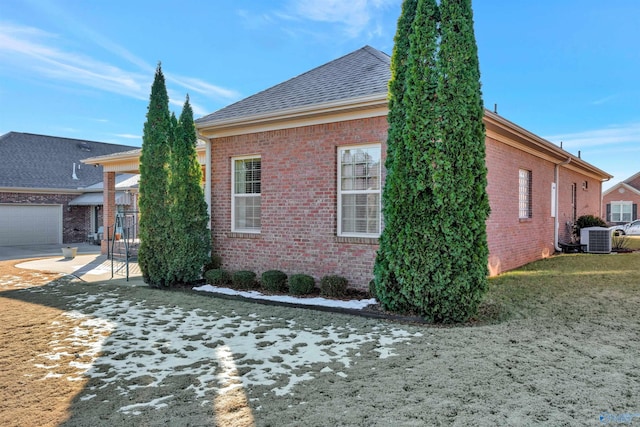 view of side of home with central AC and a garage