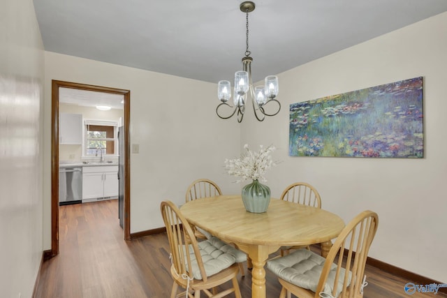 dining area featuring dark hardwood / wood-style floors, sink, and an inviting chandelier