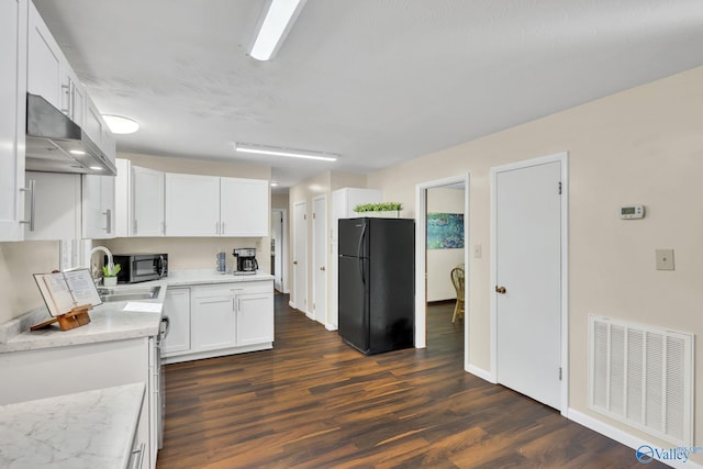 kitchen featuring black fridge, sink, dark hardwood / wood-style floors, light stone countertops, and white cabinetry