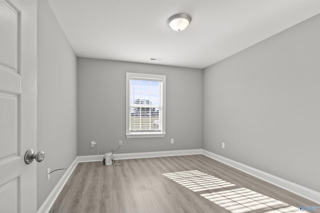 unfurnished room with visible vents, baseboards, and wood finished floors