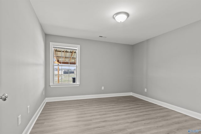 unfurnished room featuring visible vents, baseboards, and wood finished floors