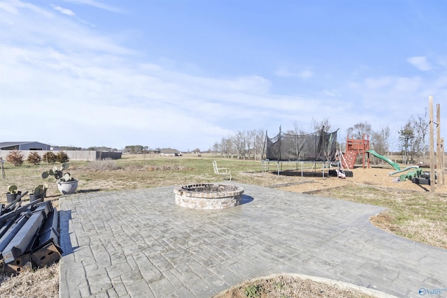 view of patio / terrace featuring a fire pit, a trampoline, and a playground