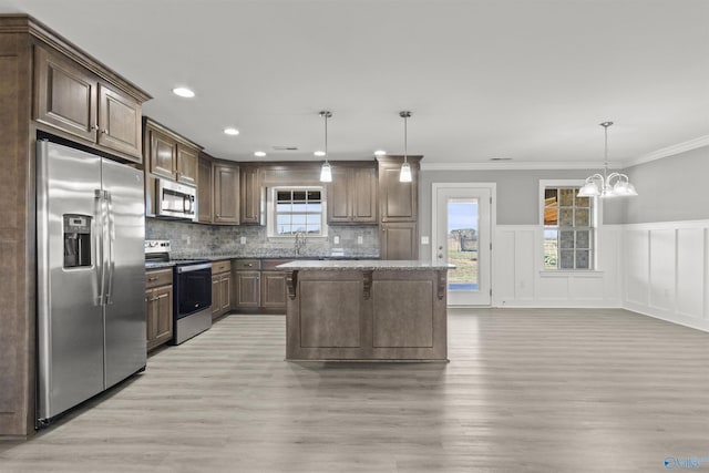 kitchen with decorative backsplash, light wood finished floors, a notable chandelier, and appliances with stainless steel finishes