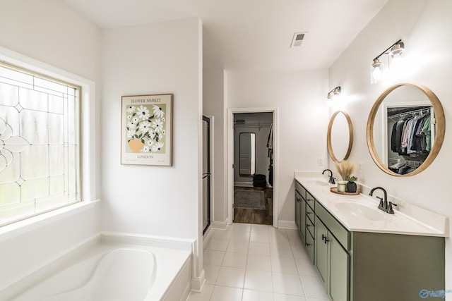 7326 Vidette Ln SE, Owens Cross Roads, AL 35763 - bathroom featuring double vanity, a garden tub, a spacious closet, tile patterned flooring, and a shower with door
