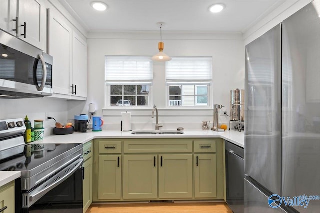 kitchen with white cabinets, stainless steel appliances, sink, hanging light fixtures, and crown molding