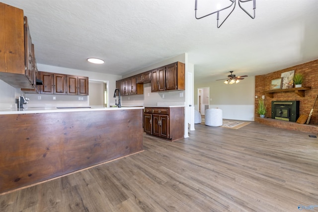 814 E Haven Dr, Glencoe, AL 35905 - kitchen with open floor plan, wood finished floors, light countertops, a brick fireplace, and a ceiling fan