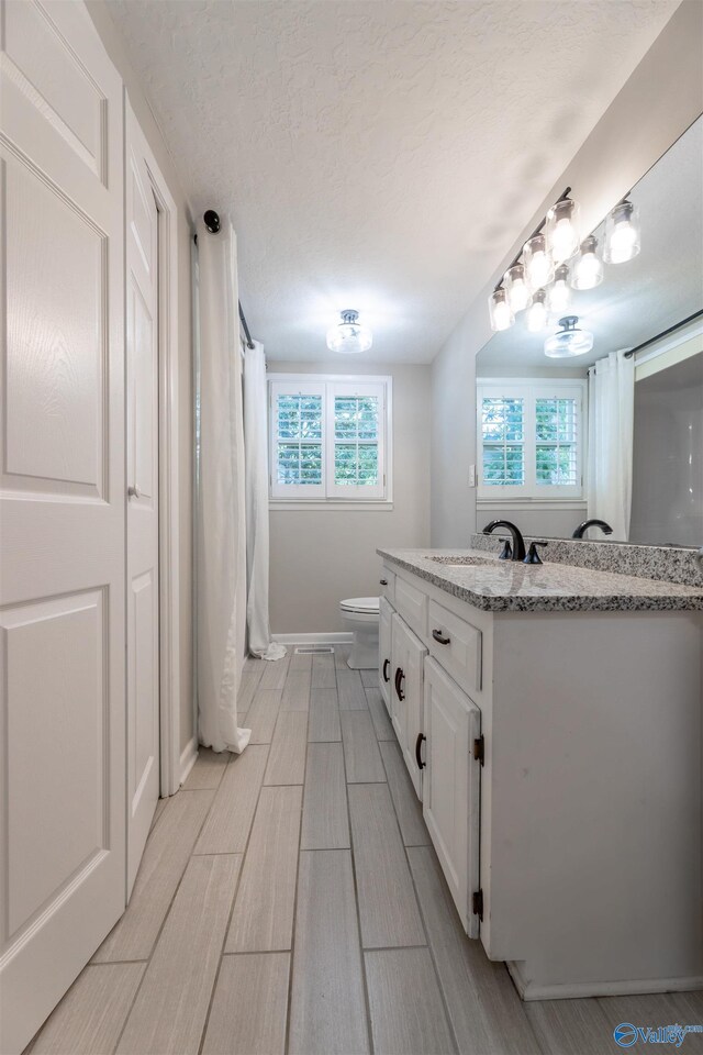 814 E Haven Dr, Glencoe, AL 35905 - full bath with vanity, a textured ceiling, a shower with shower curtain, and wood finish floors
