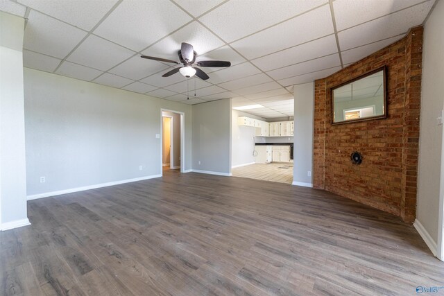 814 E Haven Dr, Glencoe, AL 35905 - unfurnished living room with a drop ceiling, ceiling fan, wood finished floors, and brick wall
