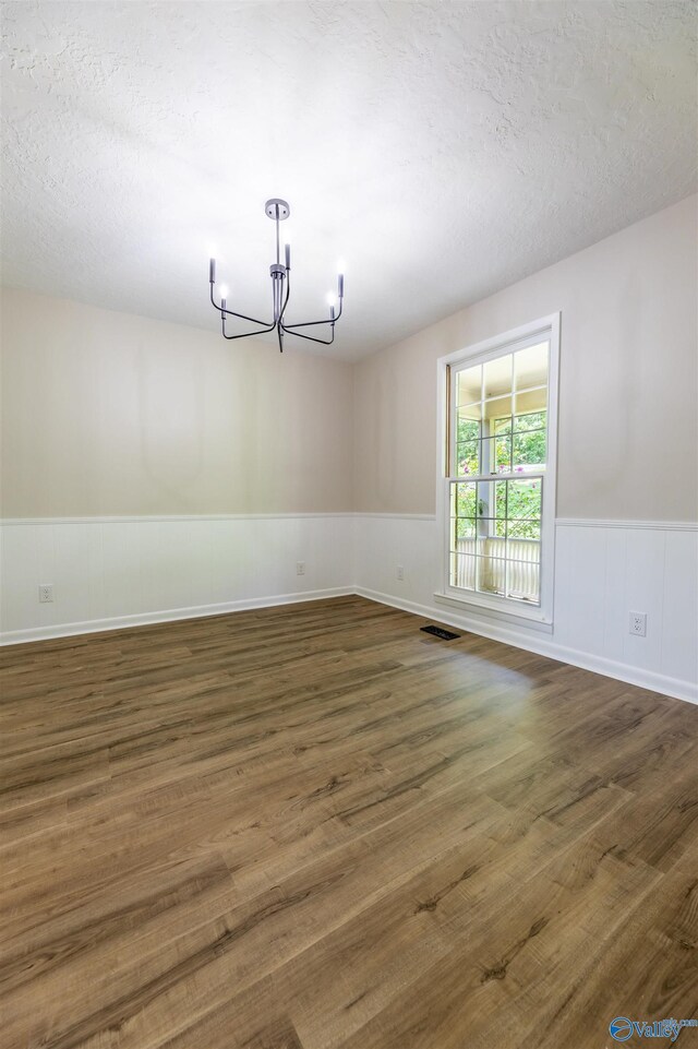 814 E Haven Dr, Glencoe, AL 35905 - unfurnished dining area with a chandelier, wainscoting, wood finished floors, and a textured ceiling