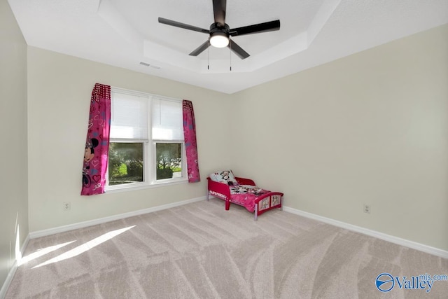 sitting room featuring ceiling fan, a tray ceiling, and light colored carpet