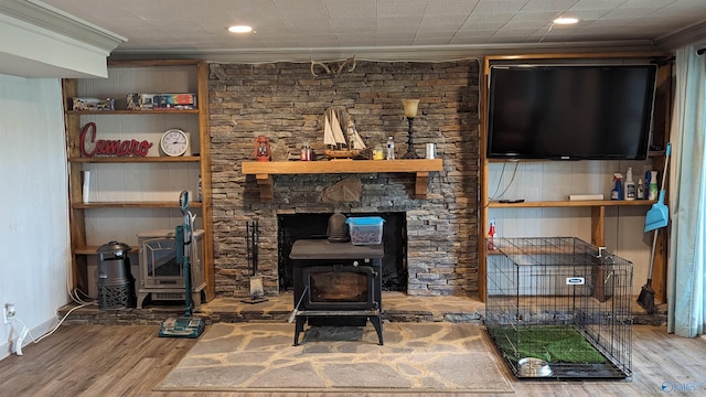 living area with a wood stove, crown molding, and wood finished floors