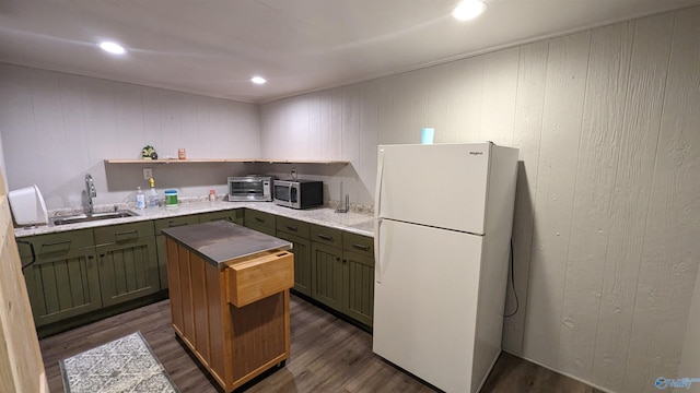 kitchen with green cabinets, stainless steel microwave, a sink, and freestanding refrigerator