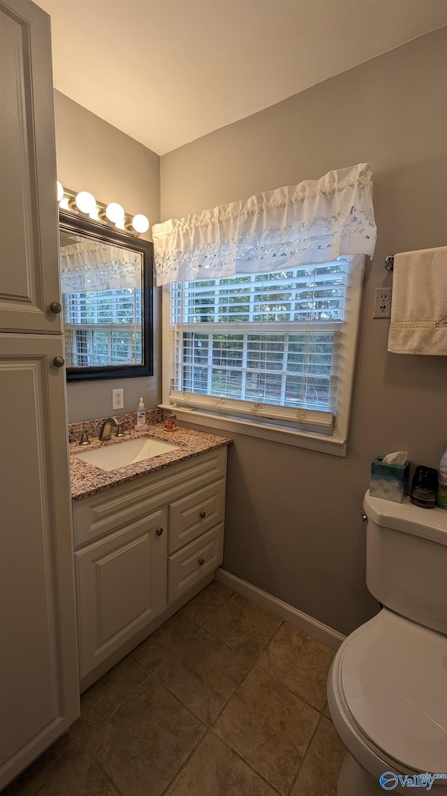 bathroom featuring toilet, tile patterned floors, baseboards, and vanity