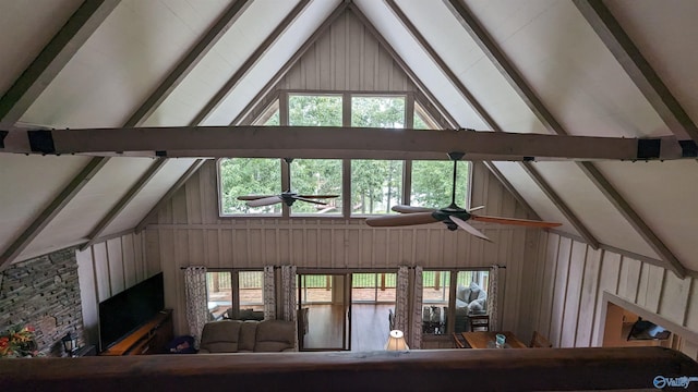 interior space with beam ceiling, ceiling fan, and wooden walls