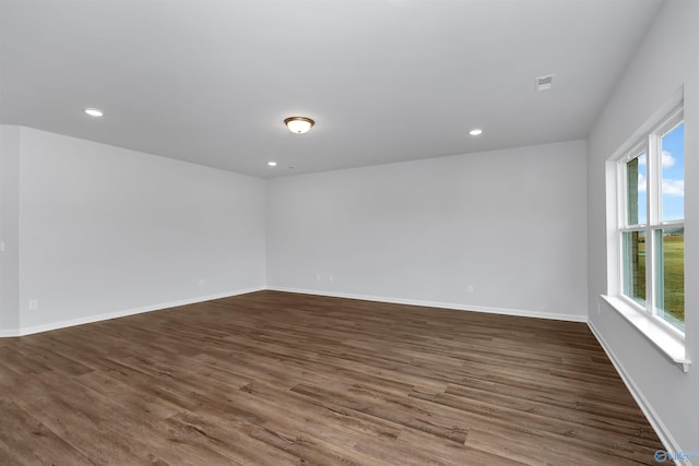 spare room featuring a healthy amount of sunlight and dark hardwood / wood-style floors