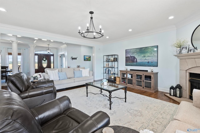 living room featuring crown molding, ornate columns, wood-type flooring, and a chandelier