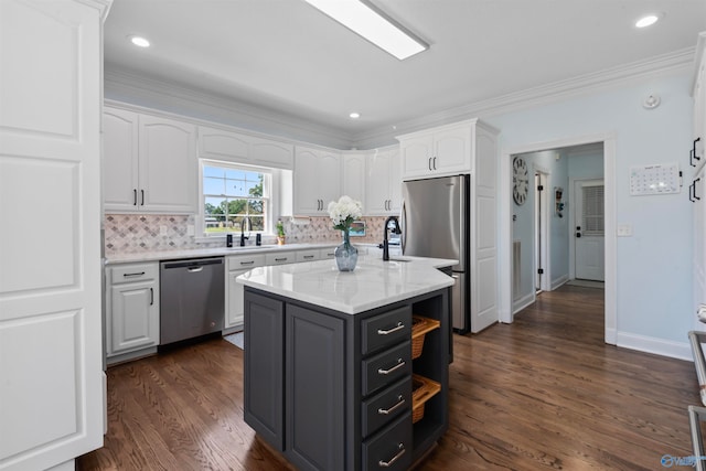 kitchen with appliances with stainless steel finishes, dark hardwood / wood-style floors, white cabinetry, and a kitchen island