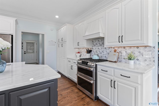 kitchen with white cabinetry, custom range hood, dark wood-type flooring, crown molding, and stainless steel appliances