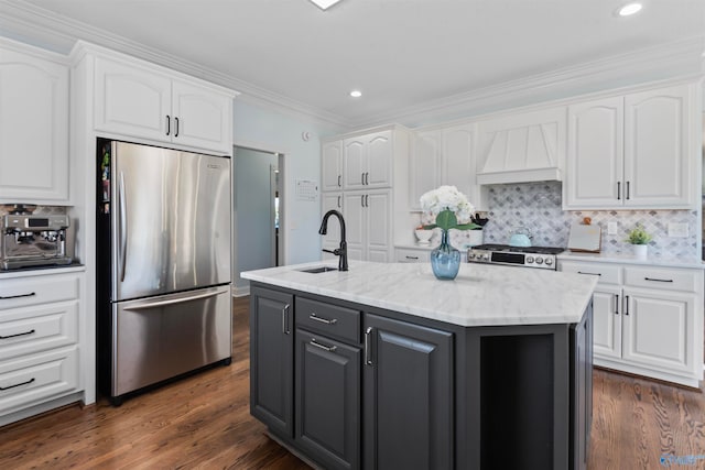 kitchen with appliances with stainless steel finishes, white cabinets, a kitchen island with sink, and sink