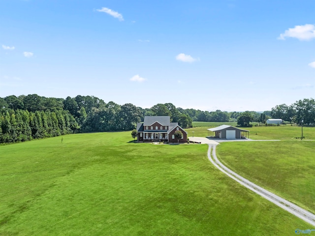 view of property's community featuring a garage, a lawn, and a rural view