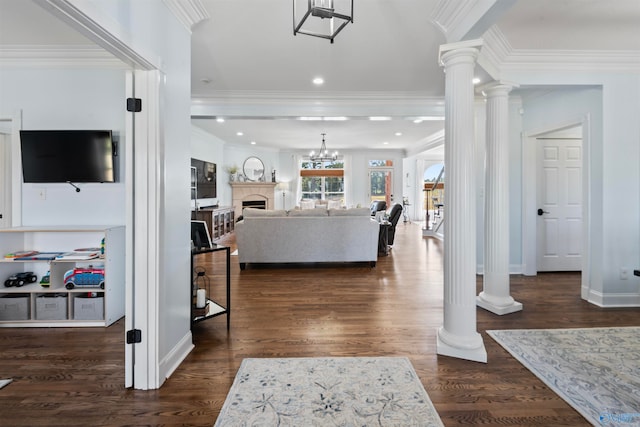 foyer featuring crown molding, dark hardwood / wood-style floors, an inviting chandelier, and decorative columns