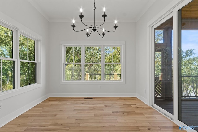 unfurnished dining area featuring a wealth of natural light, ornamental molding, light hardwood / wood-style flooring, and a notable chandelier