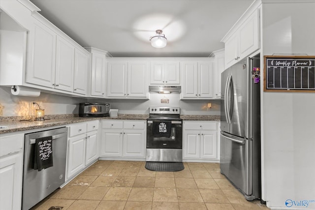 kitchen featuring light tile patterned flooring, stainless steel appliances, dark stone countertops, and white cabinetry