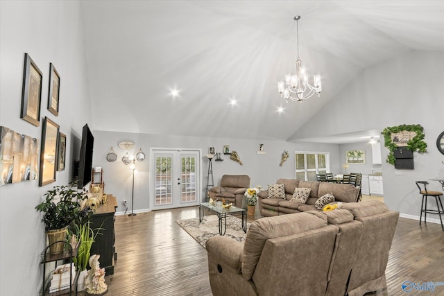 living room featuring hardwood / wood-style floors, high vaulted ceiling, french doors, and a chandelier