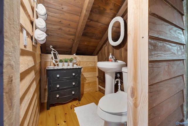 half bathroom featuring toilet, wood walls, vaulted ceiling with beams, and wood finished floors