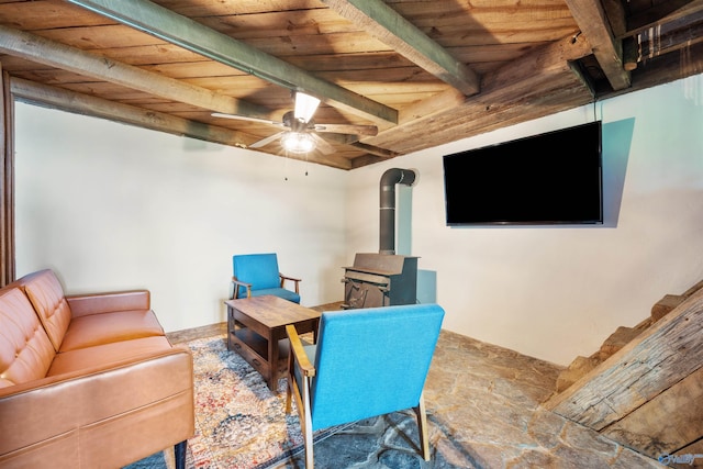 office area featuring a wood stove, beam ceiling, ceiling fan, wood ceiling, and stone finish flooring