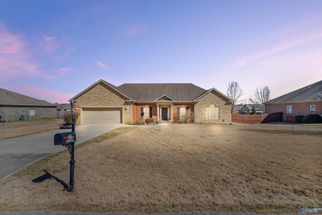 single story home with a garage, driveway, stone siding, and fence