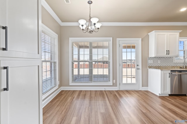 unfurnished dining area featuring ornamental molding, a wealth of natural light, and light wood-style flooring