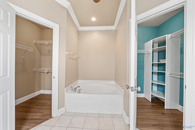 bathroom featuring ornamental molding, tile patterned flooring, a bath, and a walk in closet