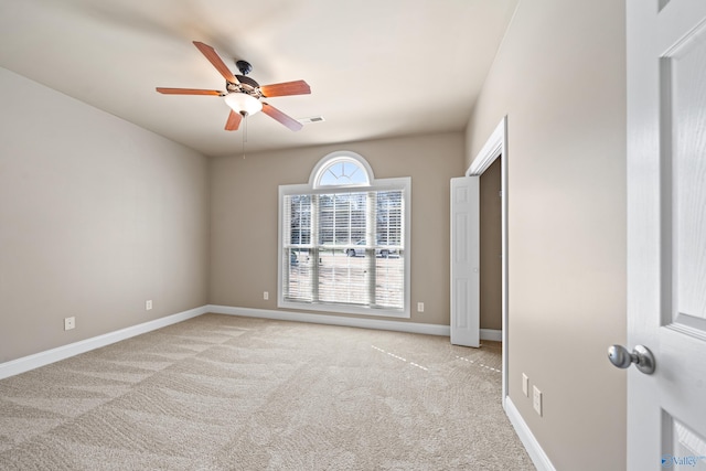 unfurnished room featuring a ceiling fan, light colored carpet, visible vents, and baseboards