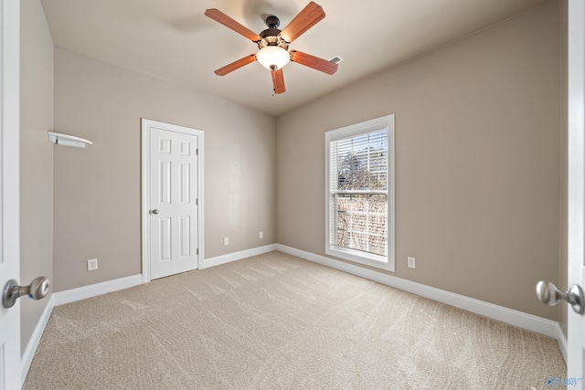 empty room featuring a ceiling fan, light carpet, and baseboards