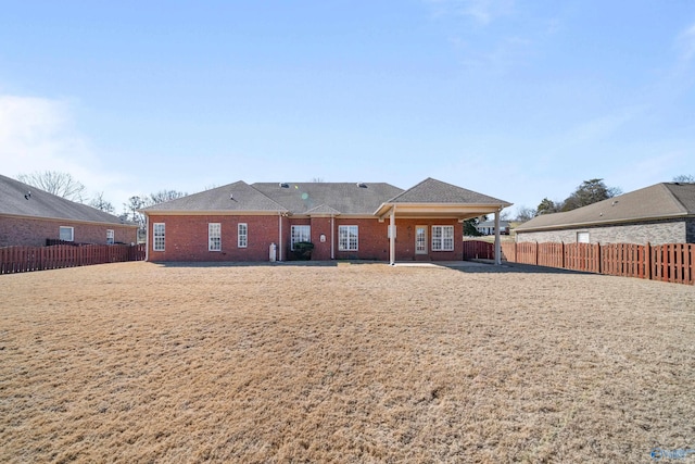 back of property with brick siding and a fenced backyard