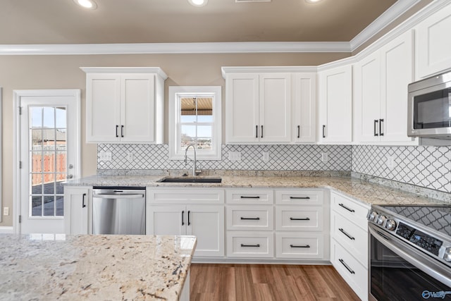 kitchen featuring stainless steel appliances, wood finished floors, a sink, white cabinetry, and crown molding