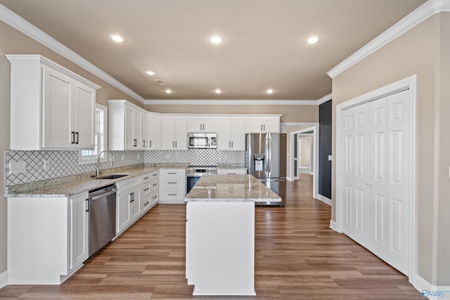 kitchen featuring stainless steel appliances, a center island, white cabinetry, and a sink